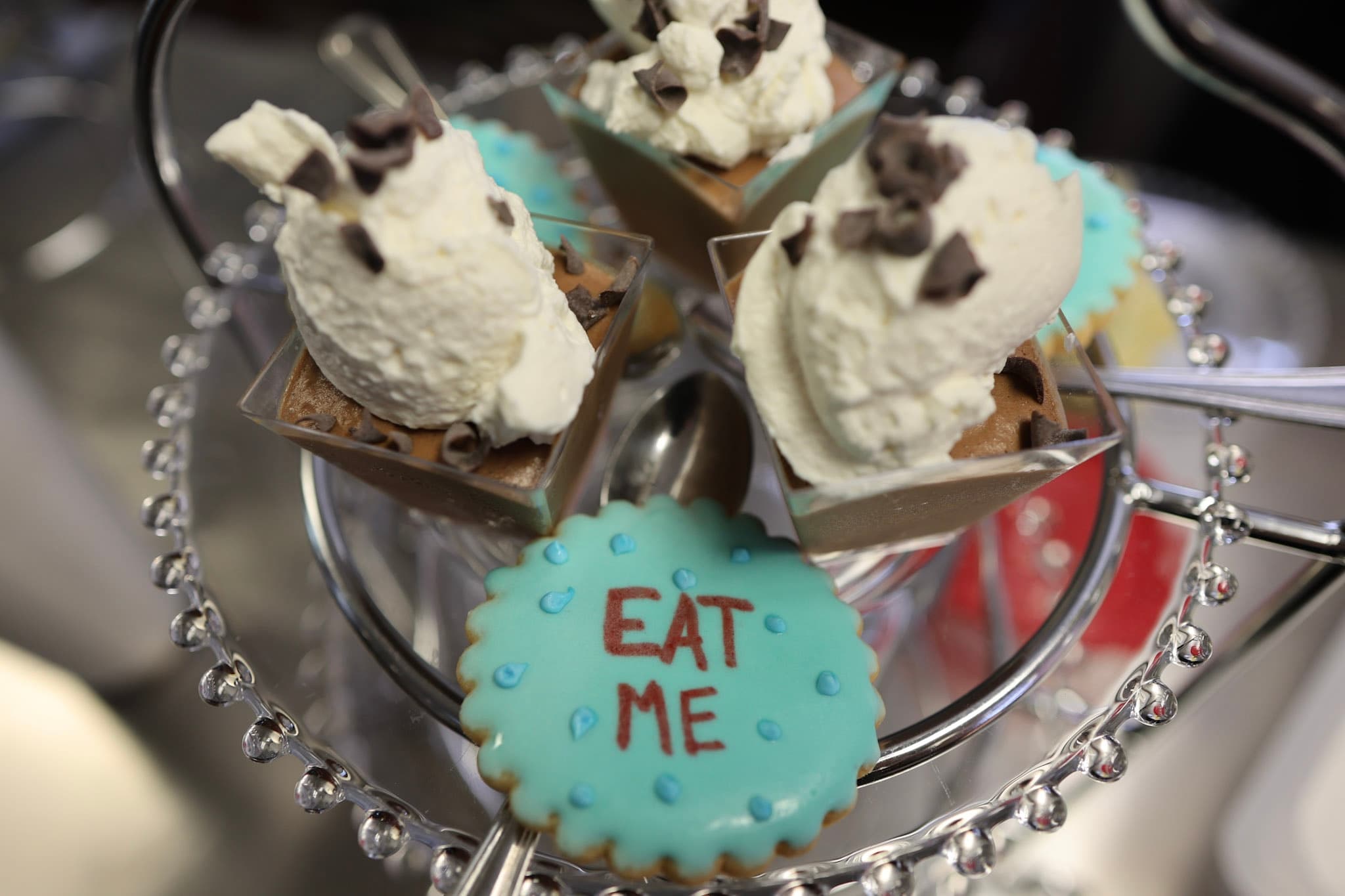 Eat Me cookie beside chocolate mousse cups on a silver tier