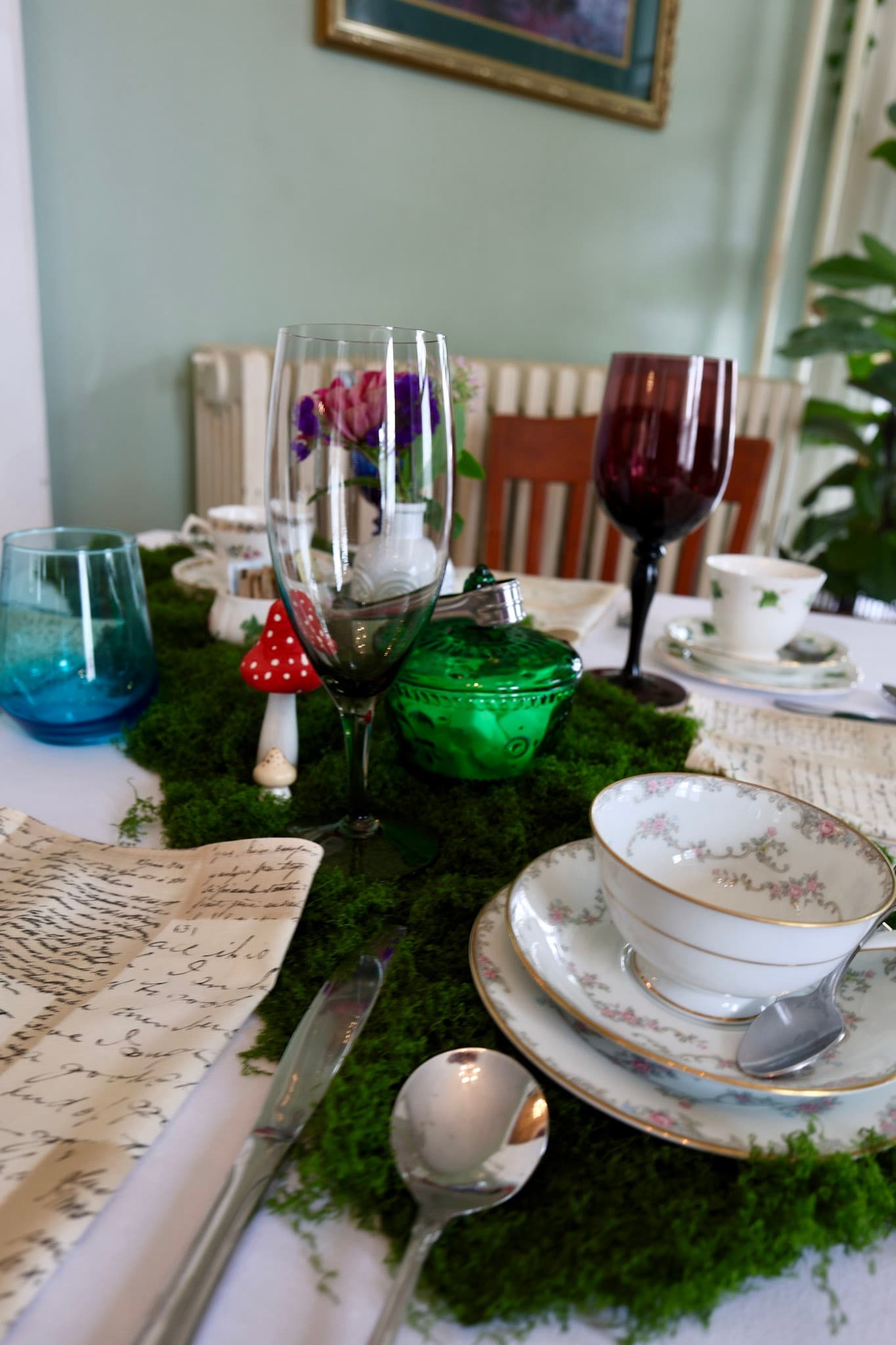 Garden moss tablescape with mushrooms, mixed china, and colorful glassware