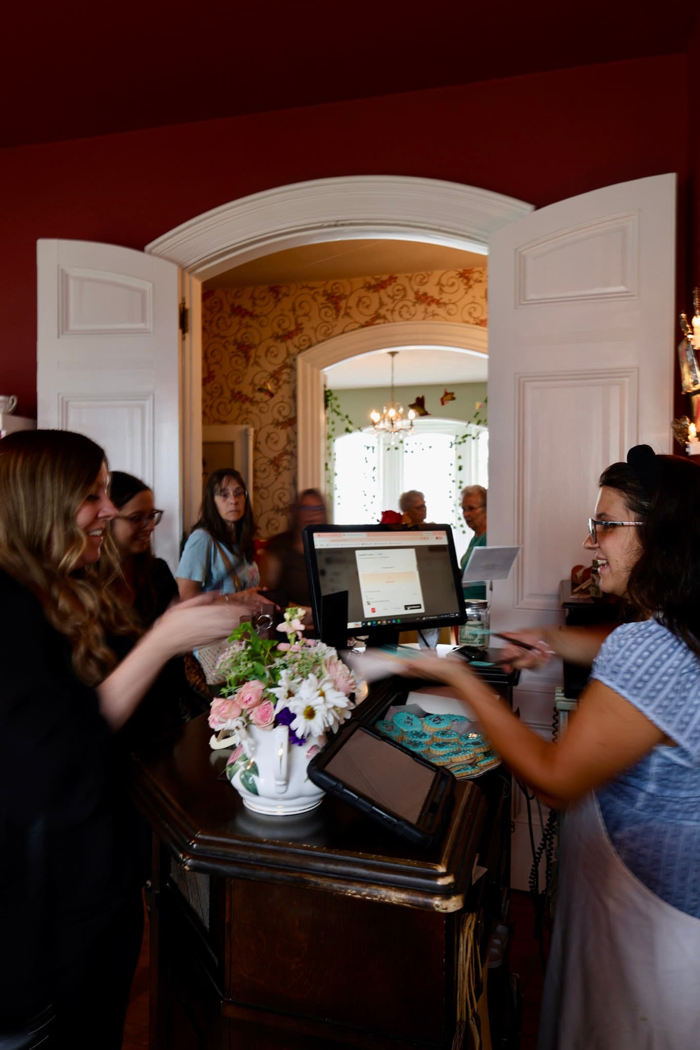 Host stand check-in with teapot floral arrangement for Alice afternoon tea