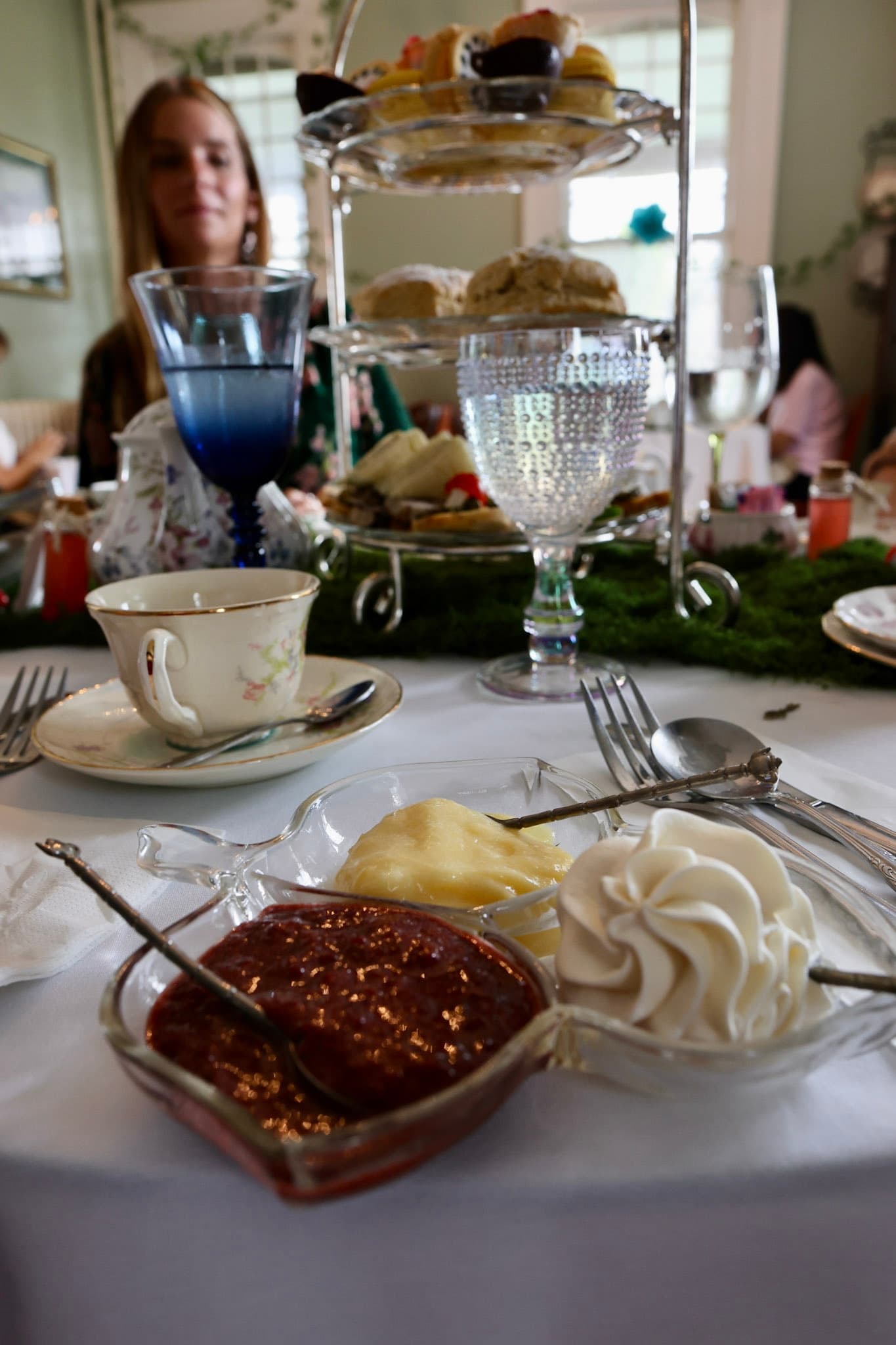 Tiered afternoon tea with moss runner, Drink Me bottles, scones, and jam