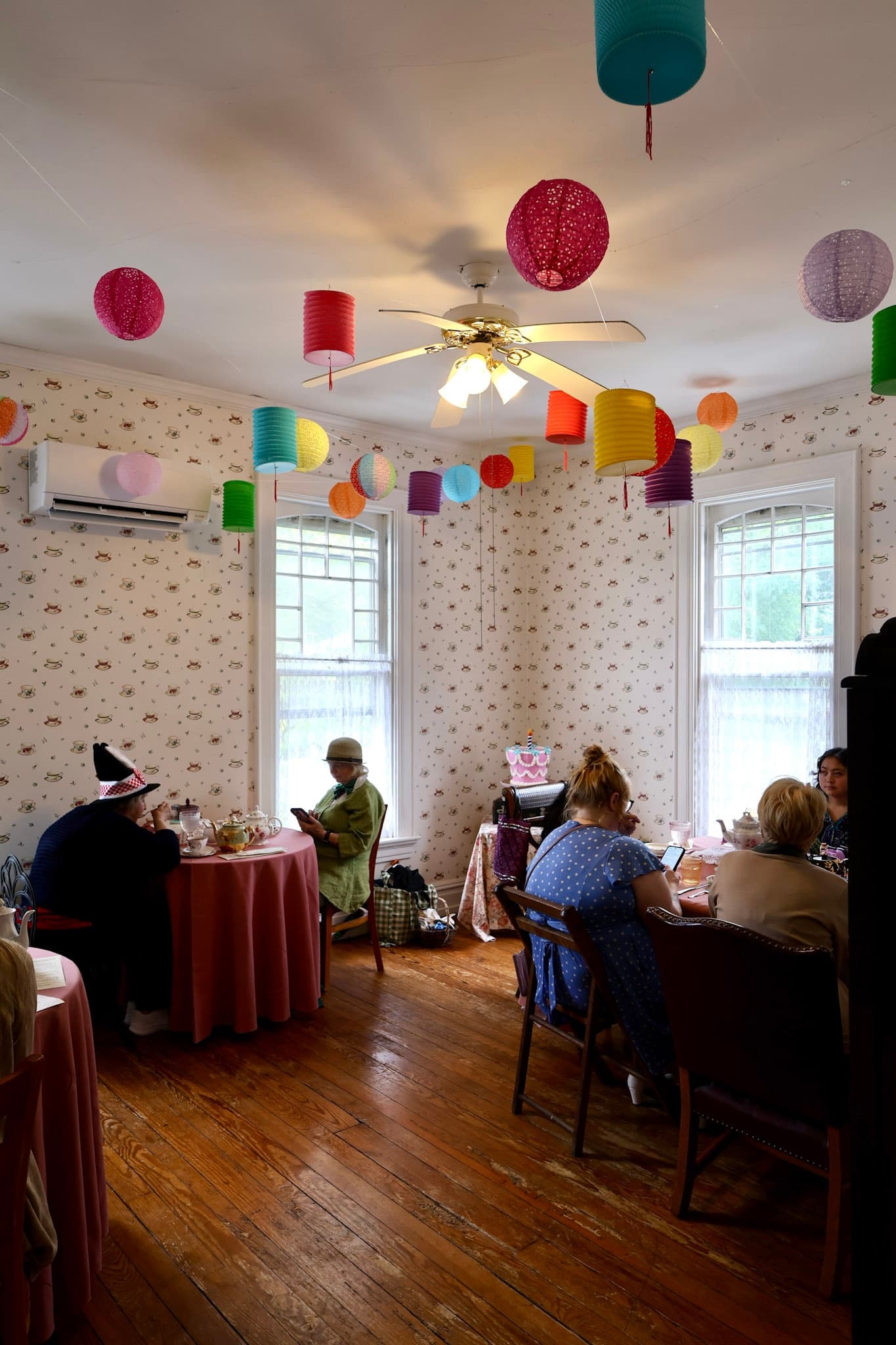 Unbirthday Room with pink tablecloths, colorful lanterns, and teacup wallpaper